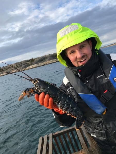 Man med hummer i handen ombord på en båt
